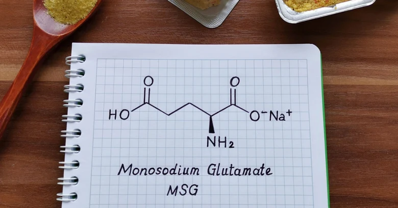 Struktura molekuly mononátriového glutamátu na sešitě vedle potravin.