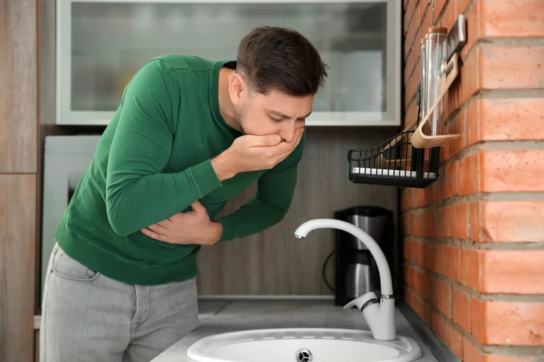 Muž se cítí nevolně u dřezu v kuchyni
