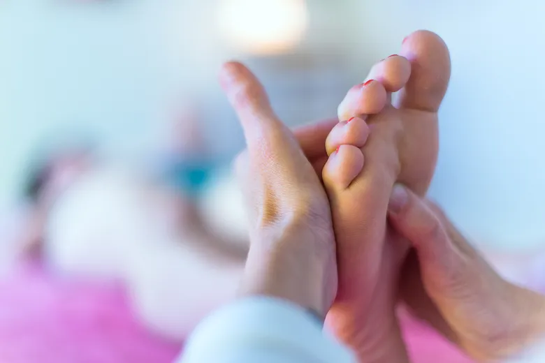 ruce masírují chodidlo při reflexní terapii
