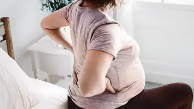 Těhotná žena drží si záda kvůli bolesti v těhotenství