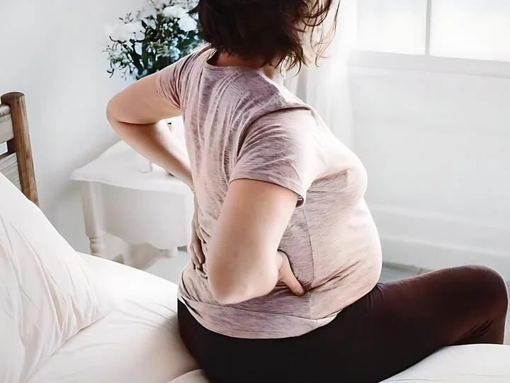 Těhotná žena drží si záda kvůli bolesti v těhotenství