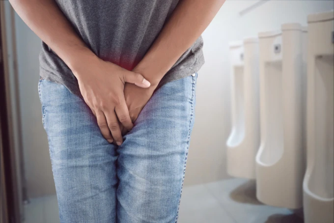Muž drží břicho v bolesti na záchodě.