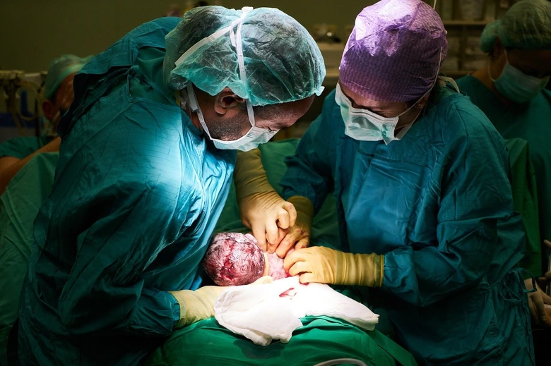 Lékaři resuscitují novorozence v nemocničním prostředí.