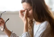 Woman rubbing eye with glasses off