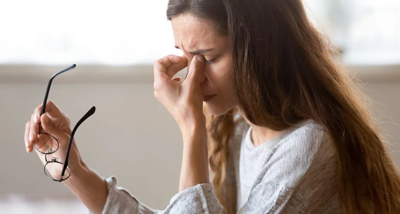 Woman rubbing eye with glasses off