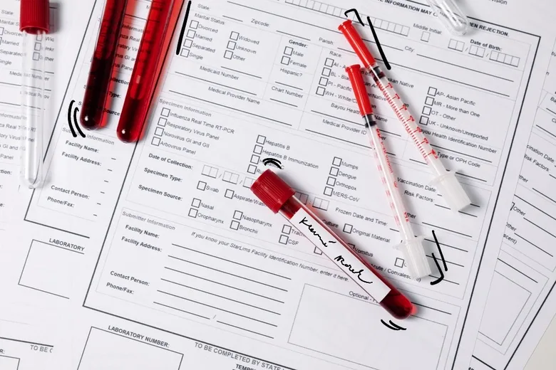 Krevní vzorky v testovacích zkumavkách s formuláři pro lékařskou analýzu.