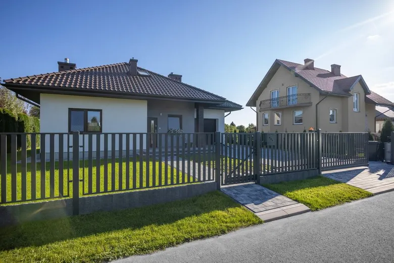 Moderní plot kolem domu s trávníkem a brankou.