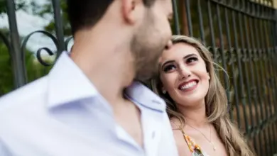 Usměvavá žena se dívá na muže před železným plotem.