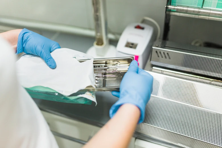 Laborant otevírá sterilizovaný nástroj v laboratoři při procesu dezinfekce.