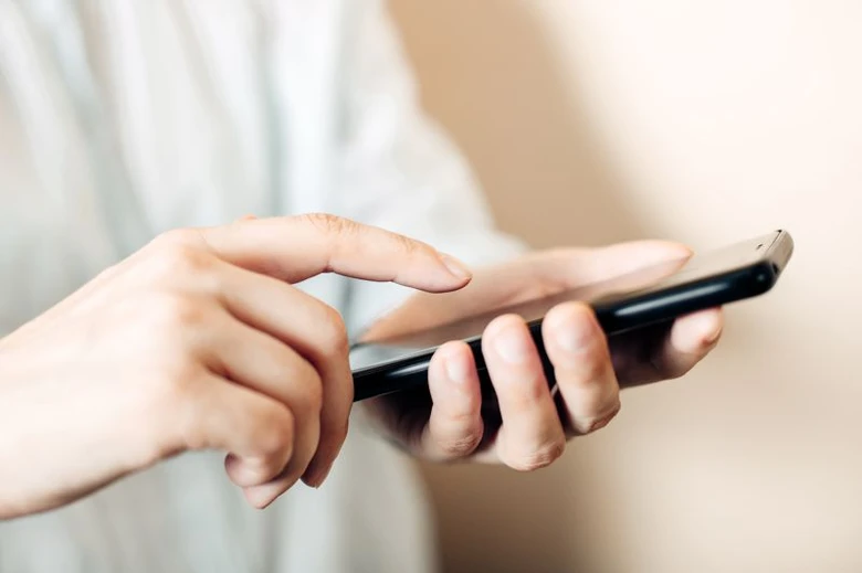 Ruce drží chytrý telefon při používání aplikace.