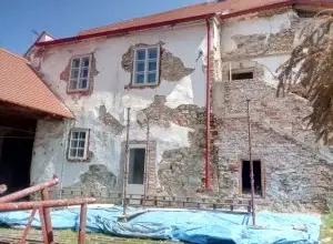 Starý dům s omítkami a cihlovou zdí během rekonstrukce.