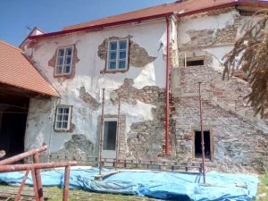 Starý dům s omítkami a cihlovou zdí během rekonstrukce.