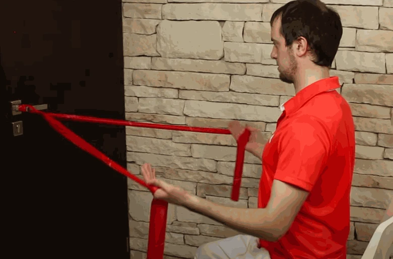 Muž cvičí s gumovou páskou pro bolestivý ramenní kloub.