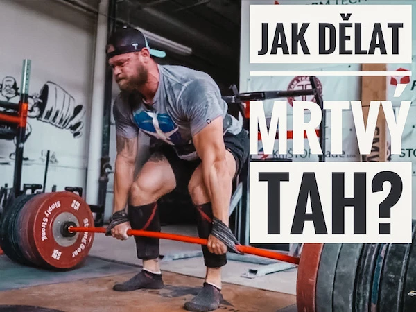 Muž dělá mrtvý tah s činkou v posilovně.